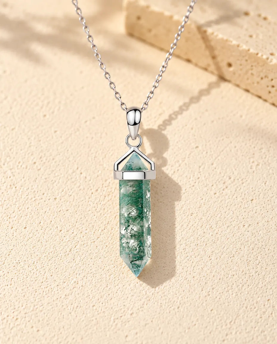 Hexagon Point Moss Agate Necklace in 925 Sterling Silver - lying on a cream textured surface beside a travertine block