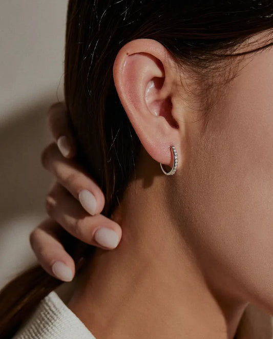Moissanite Huggie Hoop Earrings in 925 Sterling Silver - worn on a model’s ear, hand holding back her hair