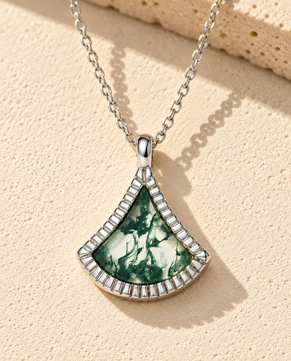Moss Agate Fan Necklace in 925 Sterling Silver - lying on a cream textured surface beside a travertine block