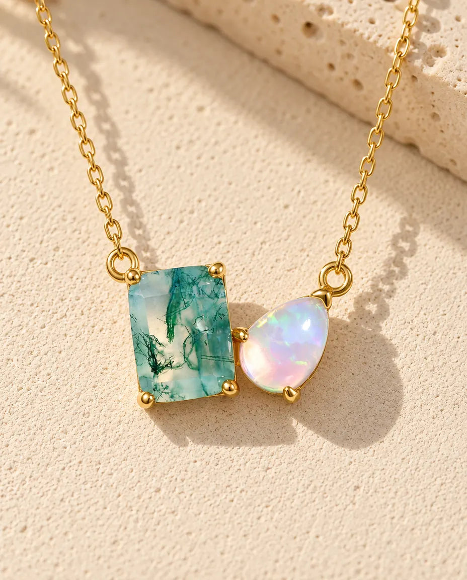 Moss Agate and Opal Necklace in 10K Gold Plated 925 Sterling Silver - lying on a cream textured surface beside a travertine block
