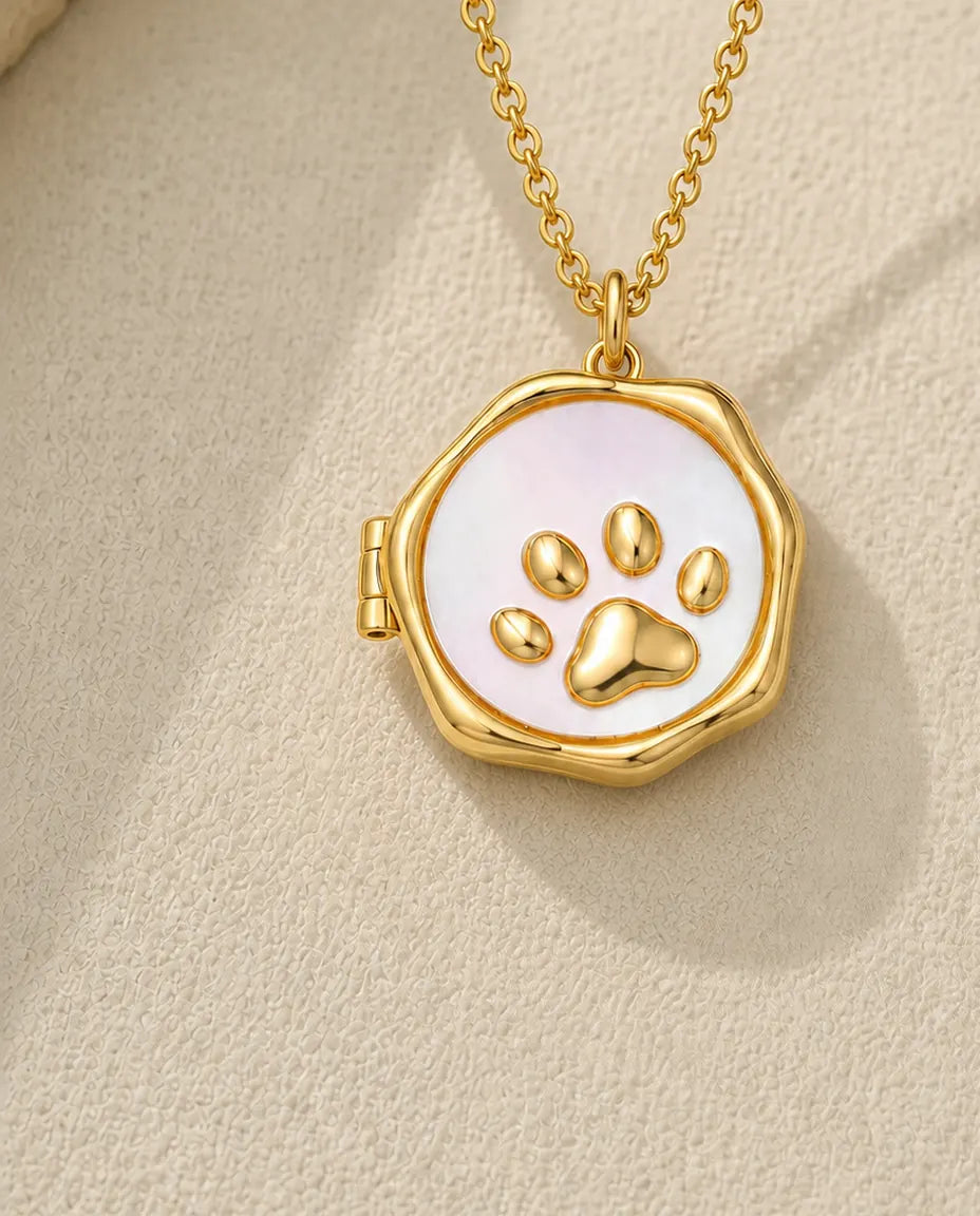 Gold paw print photo locket necklace with mother of pearl face on a cream stone