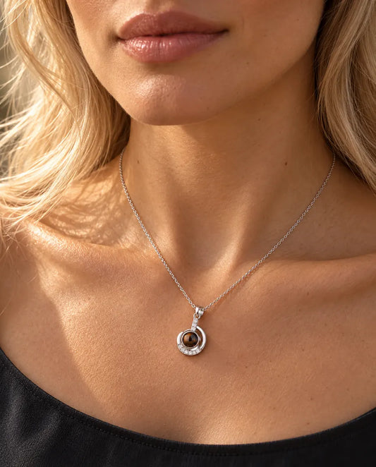 Woman in a charcoal top wearing the dainty silver tone crescent moon projection necklace