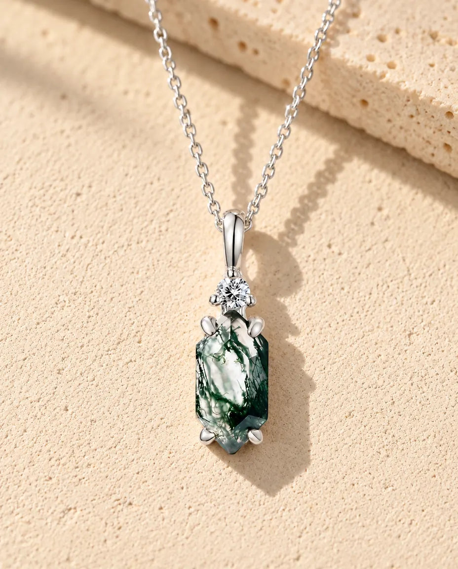 Hexagon Moss Agate Drop Necklace in 925 Sterling Silver - lying on a cream textured surface beside a travertine block