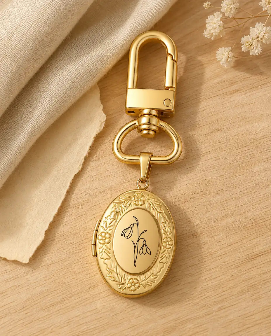 Gold birth flower photo locket keychain engraved with a snowdrop on a wood table
