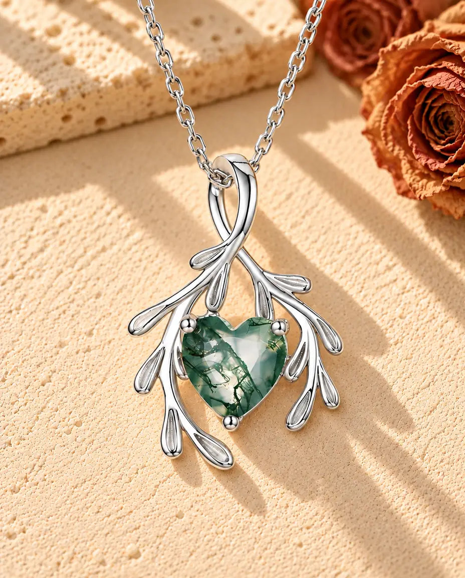 Heart Moss Agate Branch Necklace in 925 Sterling Silver - lying on a cream textured surface beside a travertine block