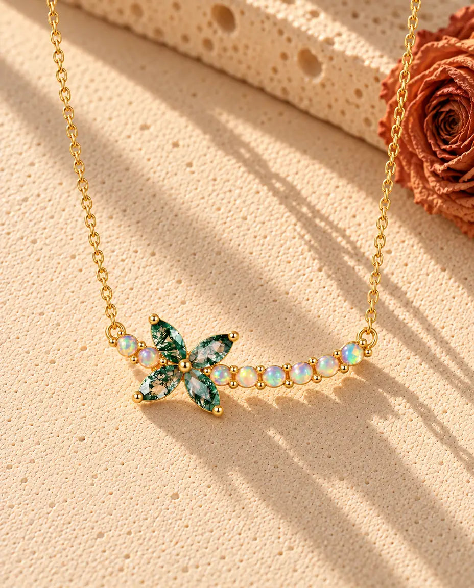 Moss Agate Flower Necklace in Gold Plated 925 Sterling Silver - lying on a cream textured surface beside a travertine block