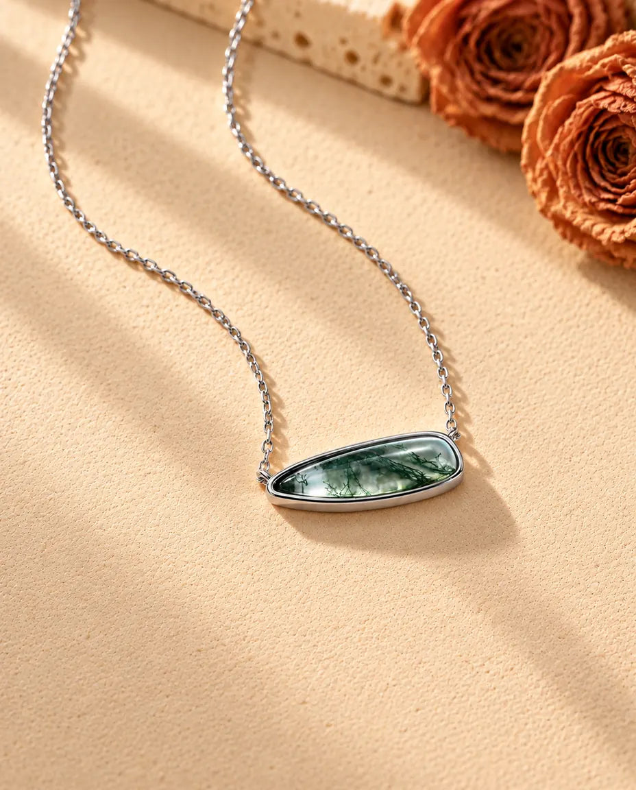 Moss Agate Bar Necklace in 925 Sterling Silver - seen at an angle on a cream textured surface