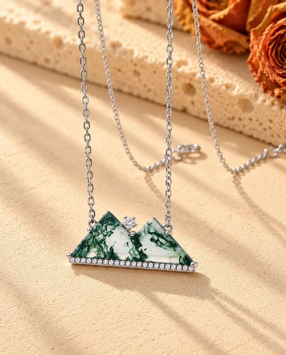 Mountain Moss Agate Necklace in 925 Sterling Silver - seen at an angle on a cream textured surface