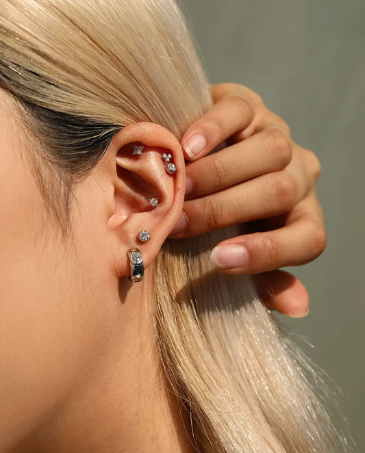 Oval Moissanite Huggie Hoop Earrings in 925 Sterling Silver - worn on a model tucking her hair behind her ear