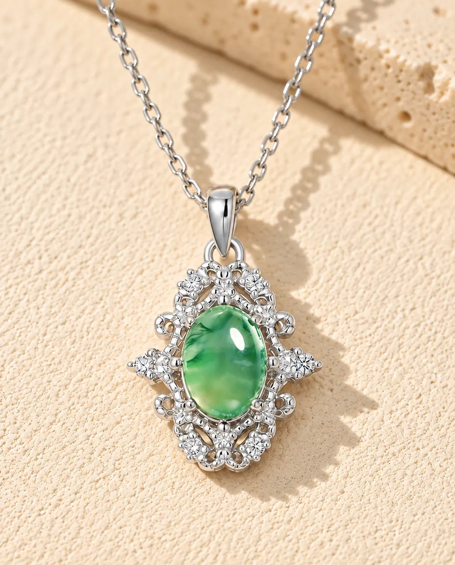 Oval Moss Agate Lace Necklace in 925 Sterling Silver - lying on a cream textured surface beside a travertine block