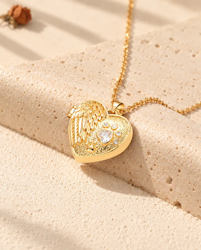 Gold tone angel wing paw print heart photo locket necklace resting on a travertine block
