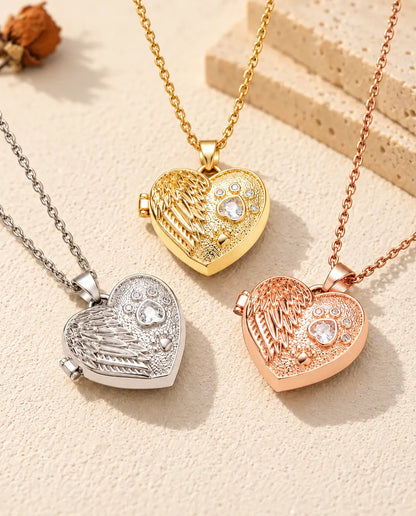 Three colors of the angel wing paw print heart photo locket necklace arranged on plaster