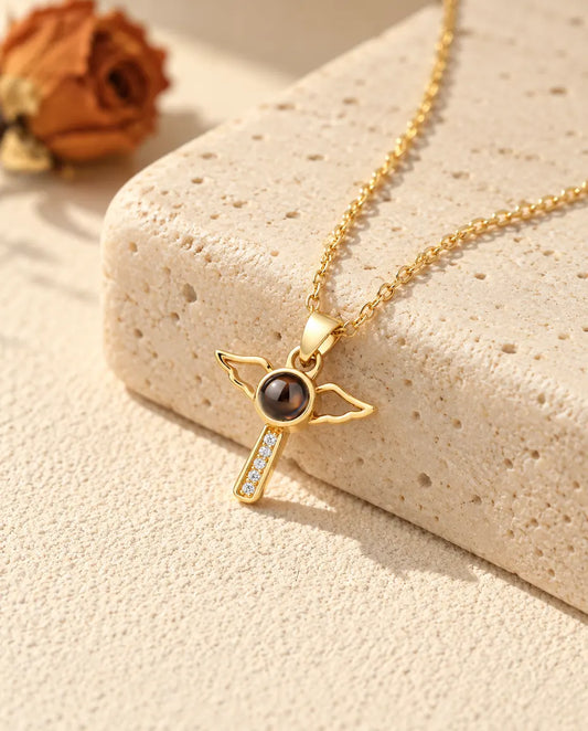 Personalized gold tone angel wings cross photo projection necklace on a travertine block