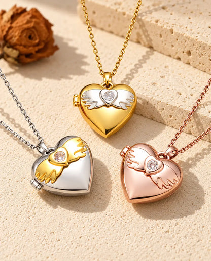 Three colors of the angel wings heart photo locket necklace arranged on plaster