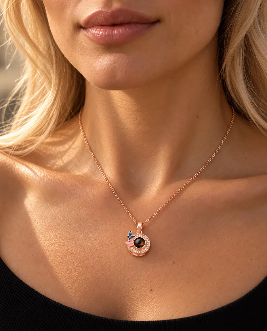 Woman in a black knit top wearing the rose gold tone butterfly circle photo projection necklace