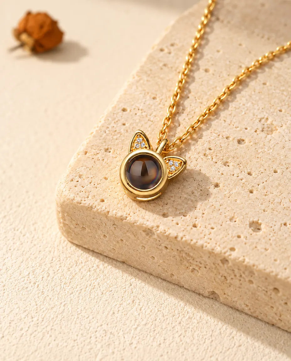 Personalized gold tone cat ear photo projection necklace on a travertine block