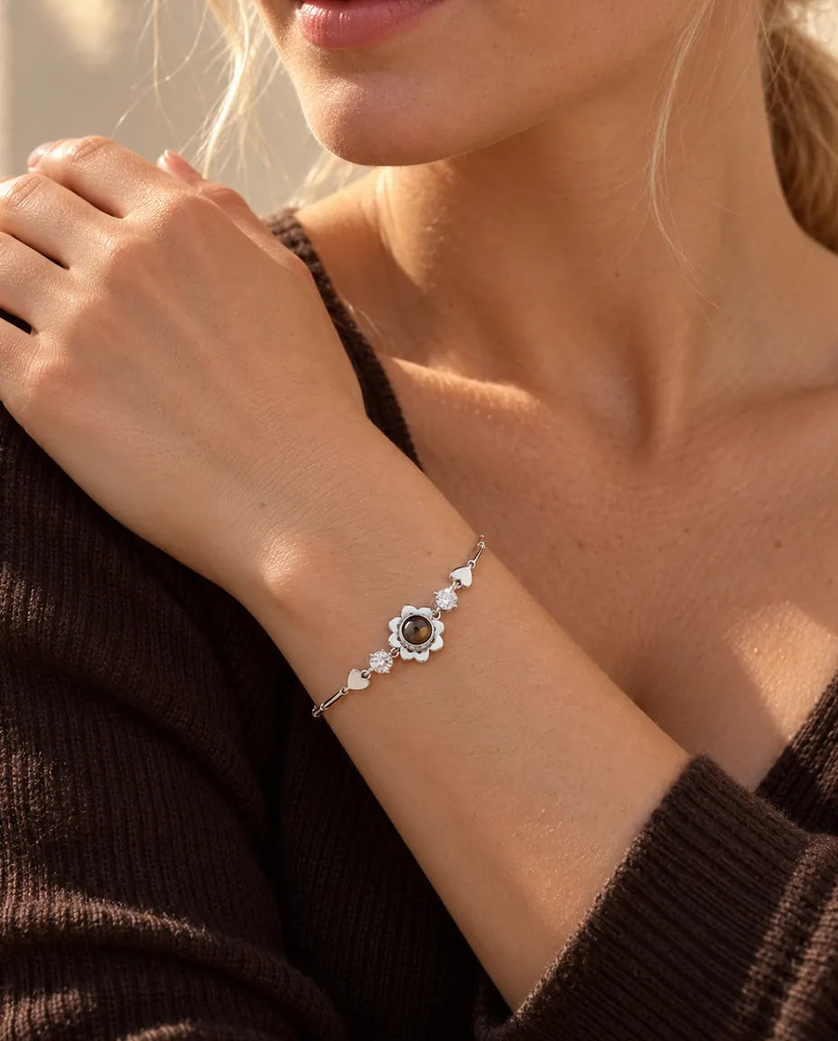 Woman resting her hand on her shoulder, wearing the silver tone clover flower projection bracelet