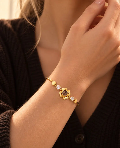 Close-up of the gold tone clover flower bracelet with heart links on a wrist near her jaw
