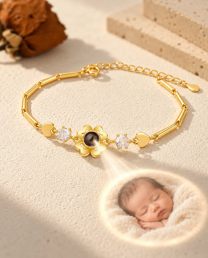 Light through the brown stone of the gold tone clover charm projects a round photo of a sleeping newborn
