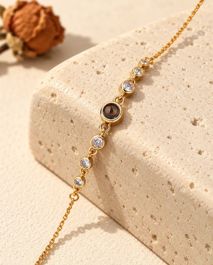 Close-up of the gold tone projection stone between bezel-set cubic zirconia on a travertine block