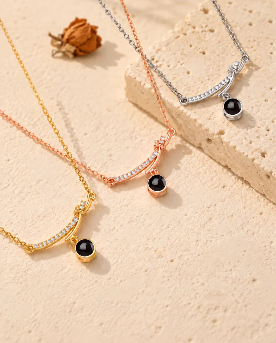 Curved bar projection necklaces in silver tone, gold tone and rose gold tone draped over travertine