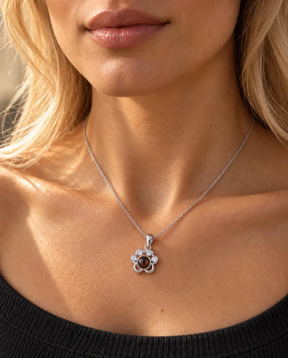 Woman in a charcoal knit top wearing the silver tone paw print projection necklace