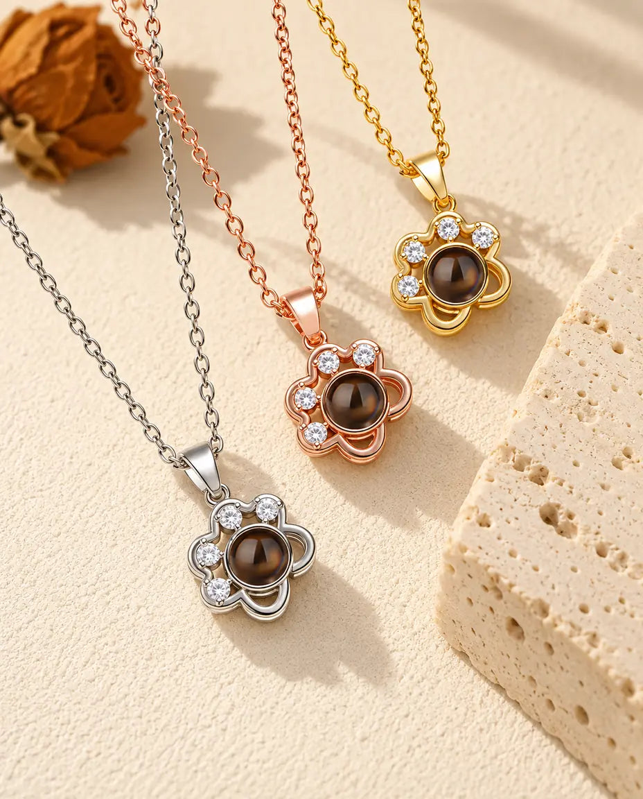 Three colors of the dainty paw print projection necklace beside a travertine block