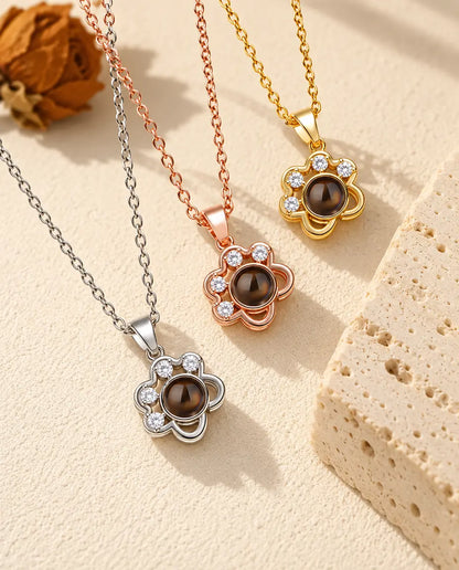 Three colors of the dainty paw print projection necklace beside a travertine block