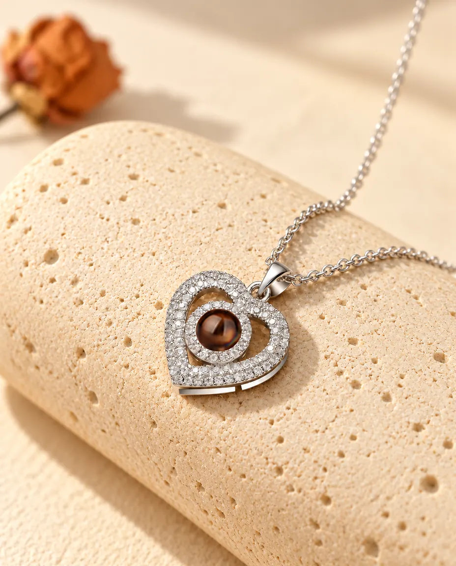 Personalized double heart photo projection necklace in silver tone with pave cubic zirconia, on a travertine block