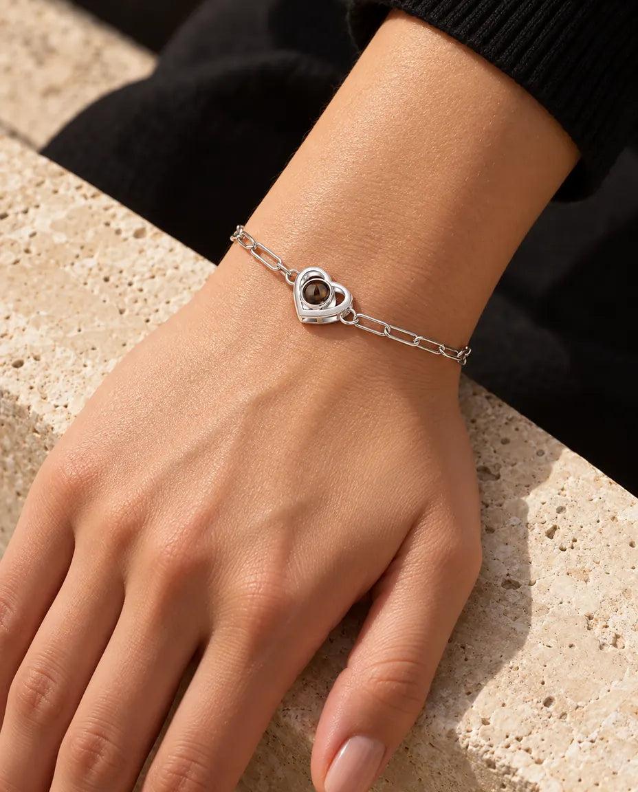 Woman wearing the silver tone double heart photo projection bracelet on her wrist in warm sunlight