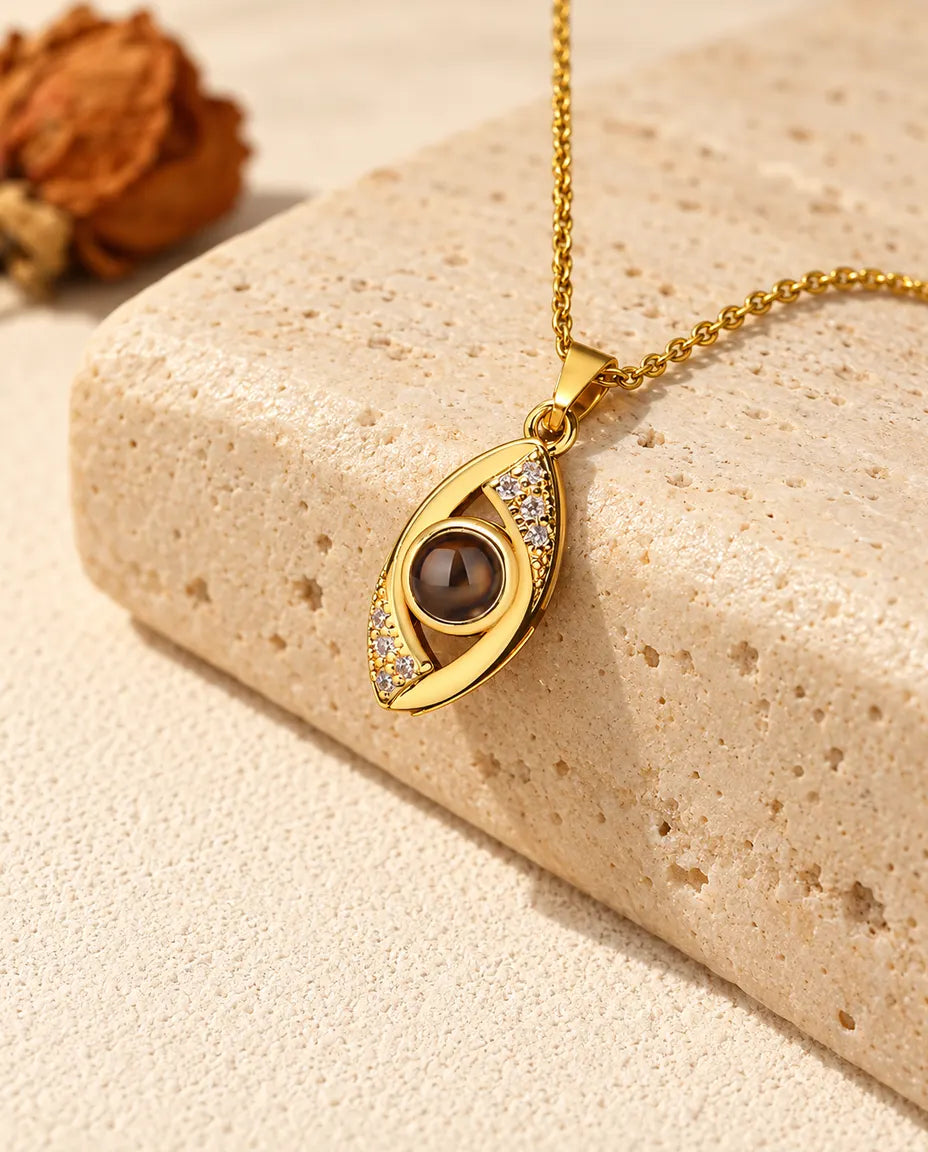 Gold tone evil eye projection necklace hanging over travertine