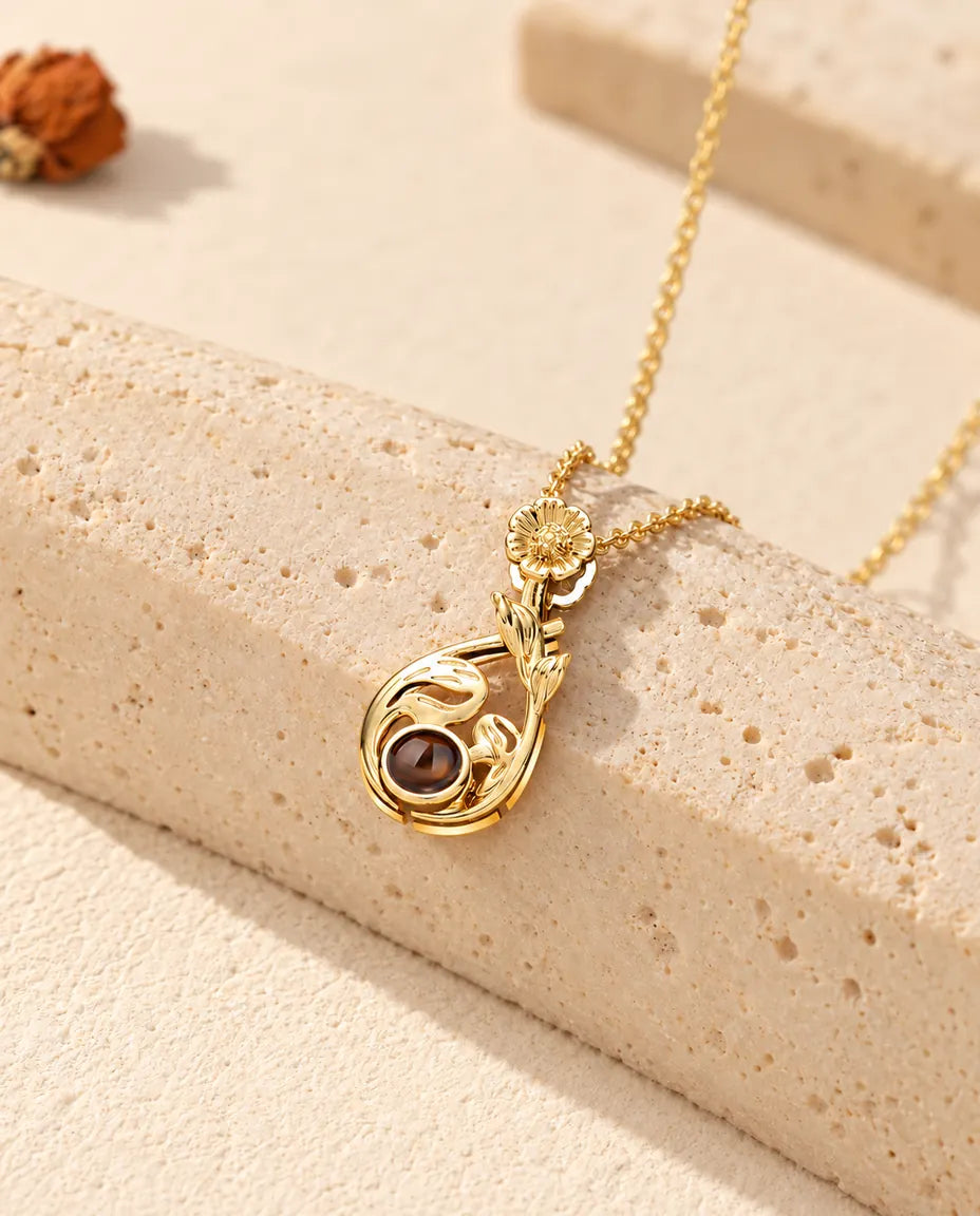 Personalized gold tone flower teardrop photo projection necklace with a daisy bail on travertine