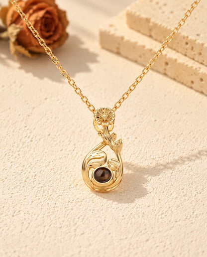 Front view of the gold tone teardrop with a daisy, leaves and the projection stone