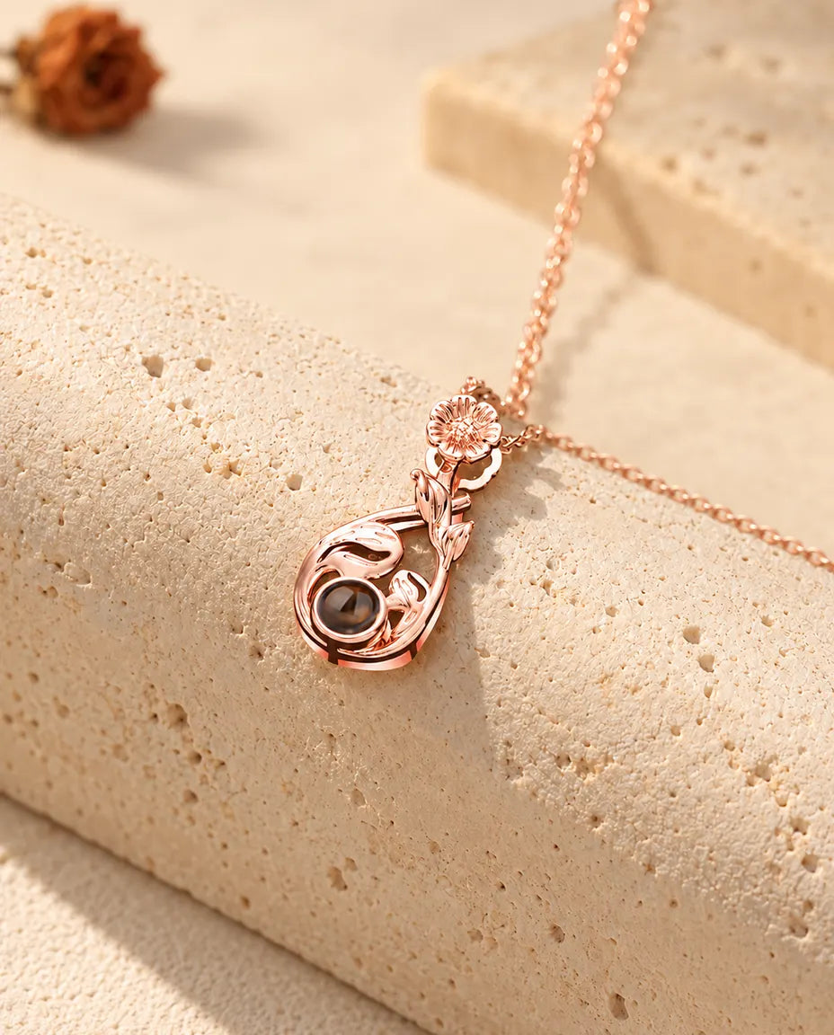 Rose gold tone flower teardrop projection necklace hanging over travertine