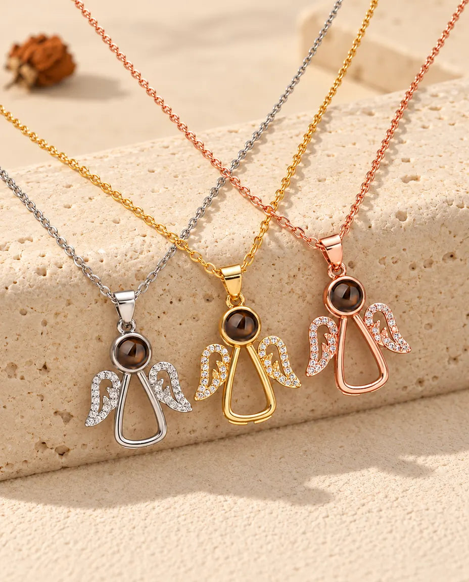 Silver tone, gold tone and rose gold tone angel necklaces hanging over a travertine block