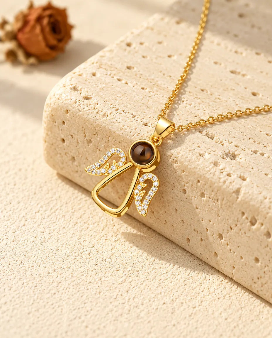 Gold tone angel projection necklace with cubic zirconia wings on travertine