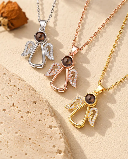 Three angel projection necklaces laid diagonally beside a travertine slab
