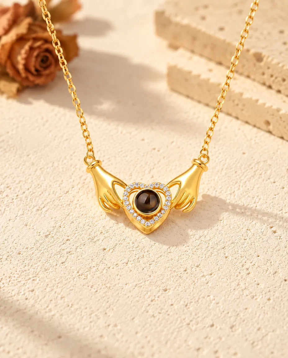 Front view of the gold tone hands holding heart pendant with chain attached at each wrist