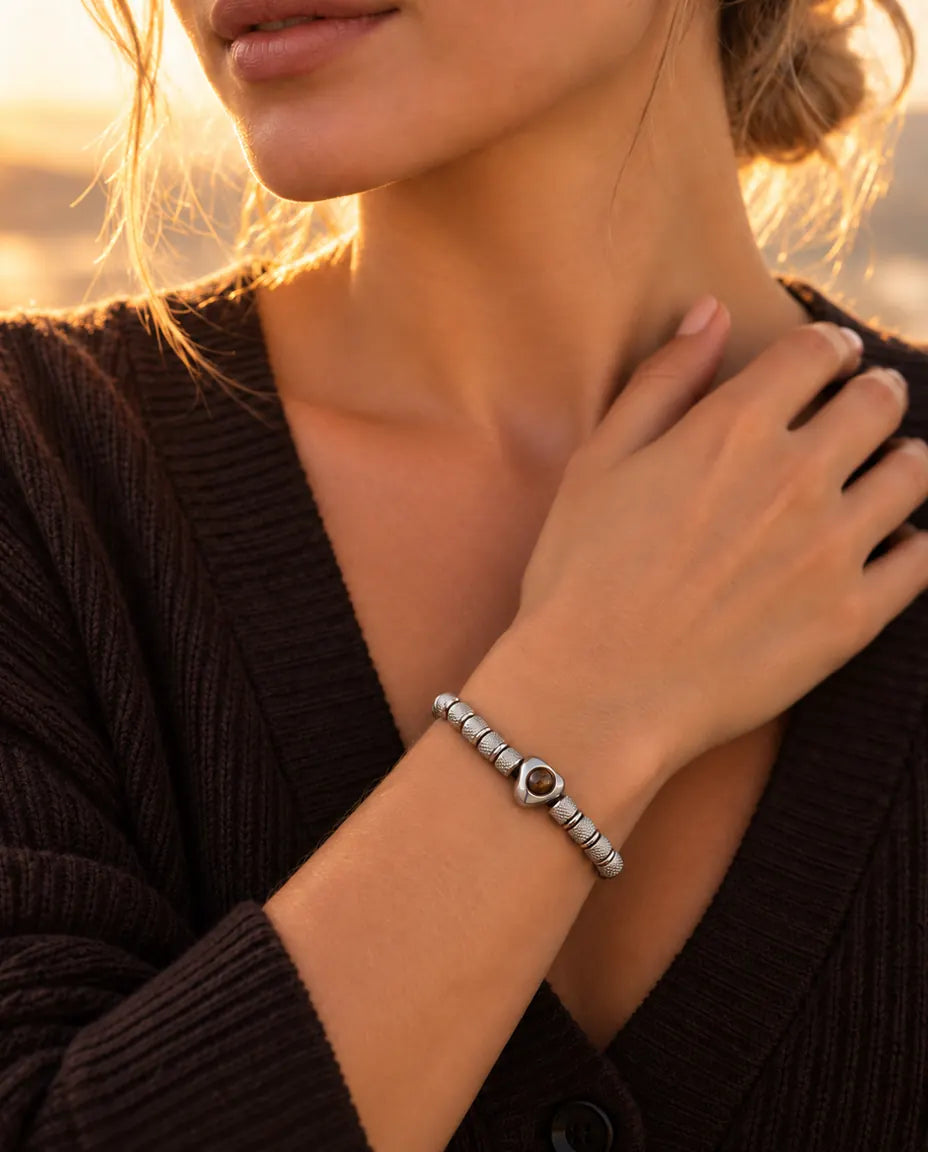 Woman with her hand at her collarbone, wearing the silver tone heart bead projection bracelet