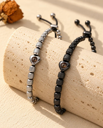 Silver tone and black heart projection bead bracelets draped over a travertine block