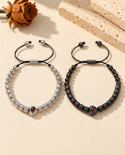 Top view of the silver tone and black couples bracelets with sliders and cord ends