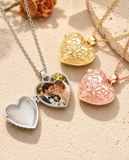 Silver tone lotus flower heart photo locket opened to show a bride and groom photo inside, beside closed gold tone and rose gold tone lockets