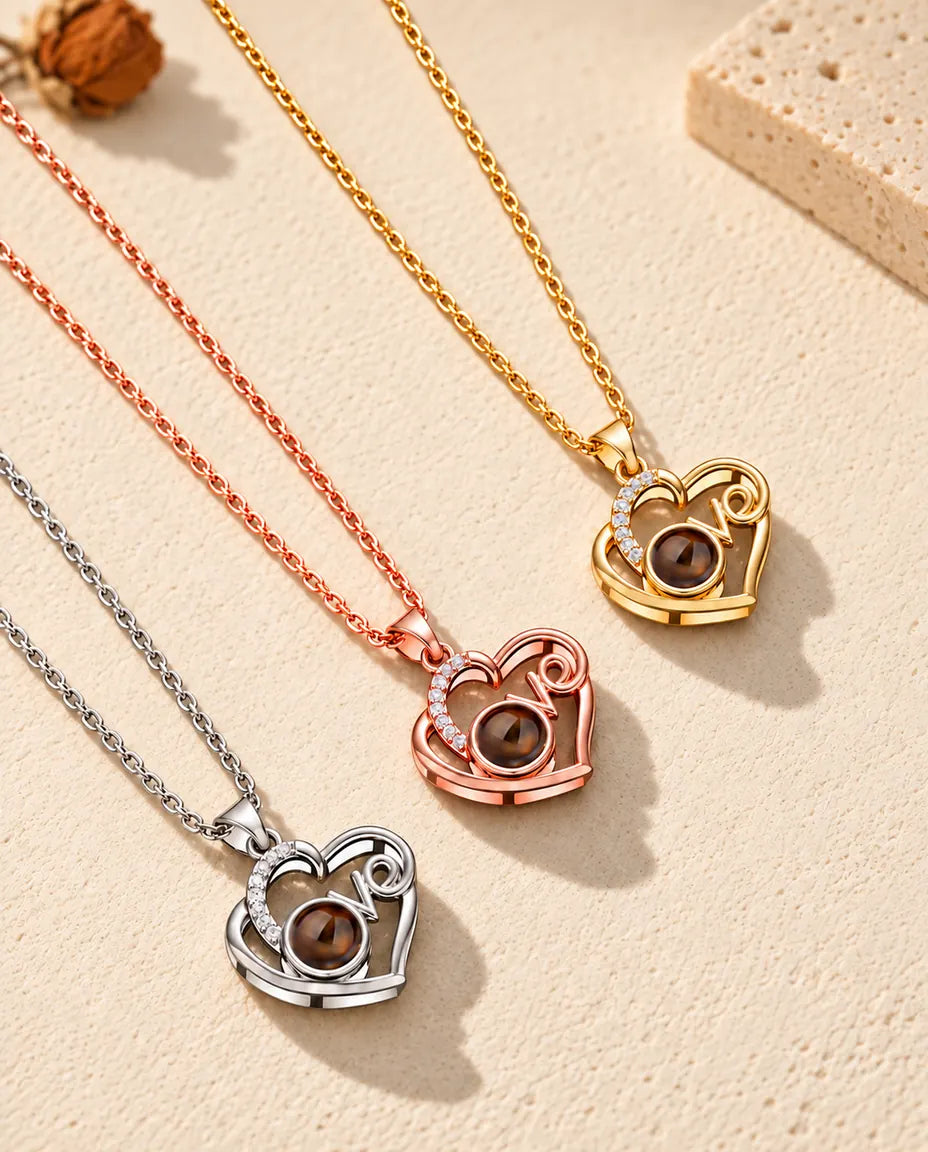 Silver tone, rose gold tone and gold tone Love heart projection necklaces laid diagonally on plaster