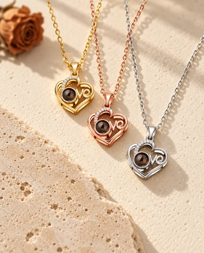 Gold tone, rose gold tone and silver tone Love heart projection pendants stacked beside a travertine slab