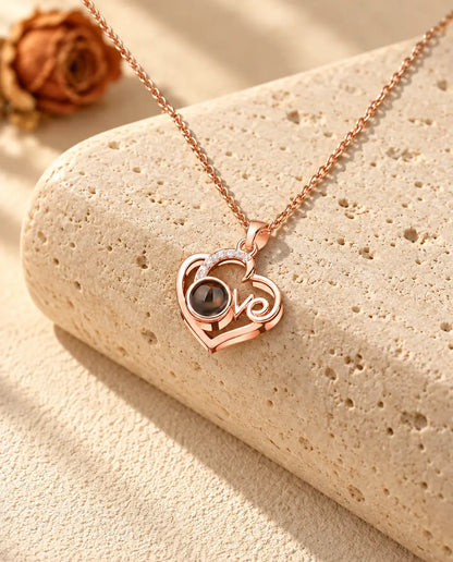 Rose gold tone Love heart photo projection necklace on travertine in warm sunlight