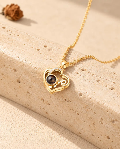 Gold tone Love heart photo projection necklace resting on a travertine block