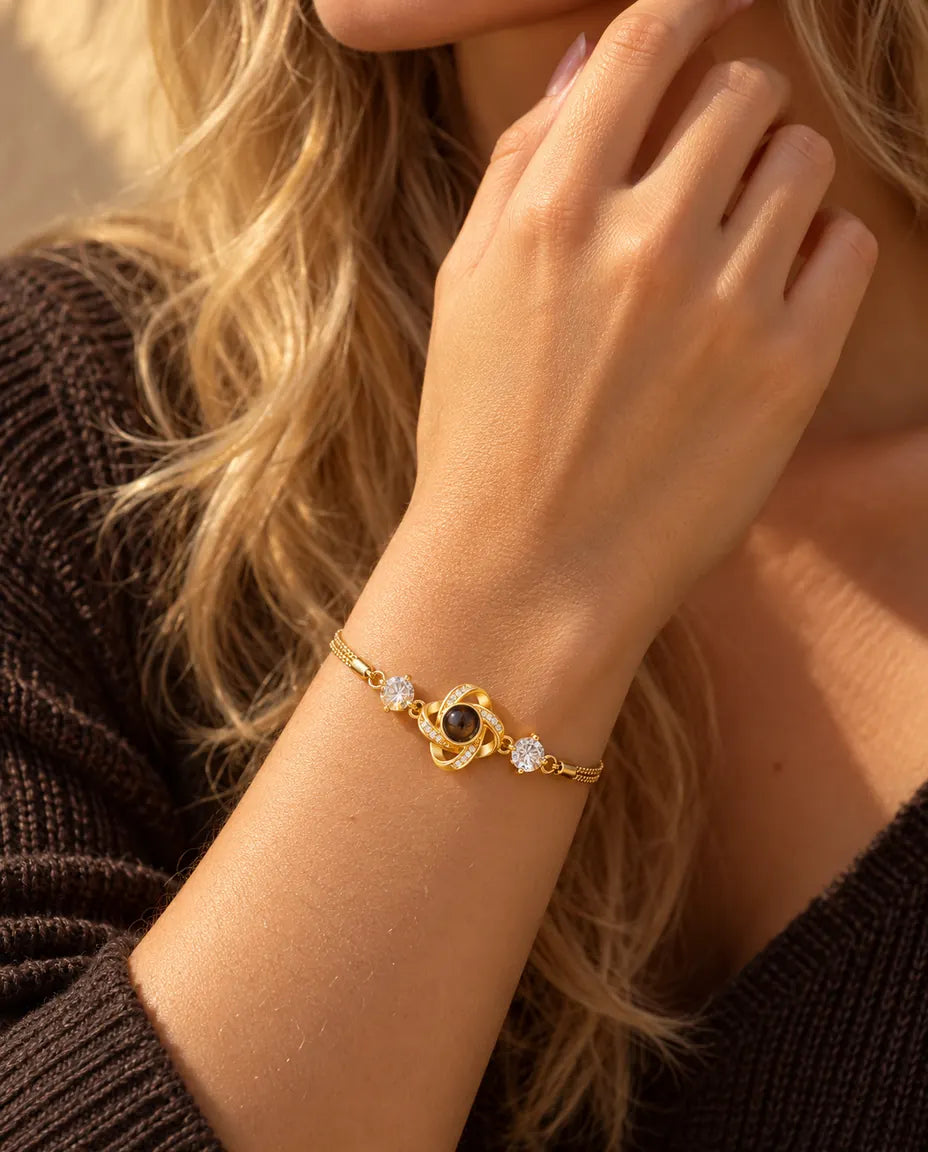 Close-up of the gold tone love knot bracelet with cubic zirconia on a wrist near her jaw