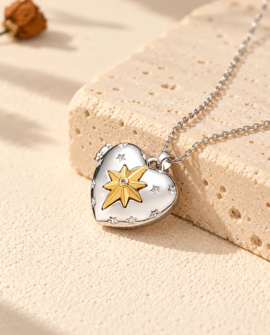 Personalized north star heart photo locket necklace in silver tone with a gold tone north star, resting on a travertine block