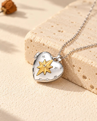 Personalized north star heart photo locket necklace in silver tone with a gold tone north star, resting on a travertine block