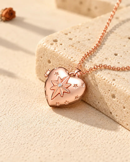 Rose gold tone north star heart photo locket necklace on travertine in warm sunlight